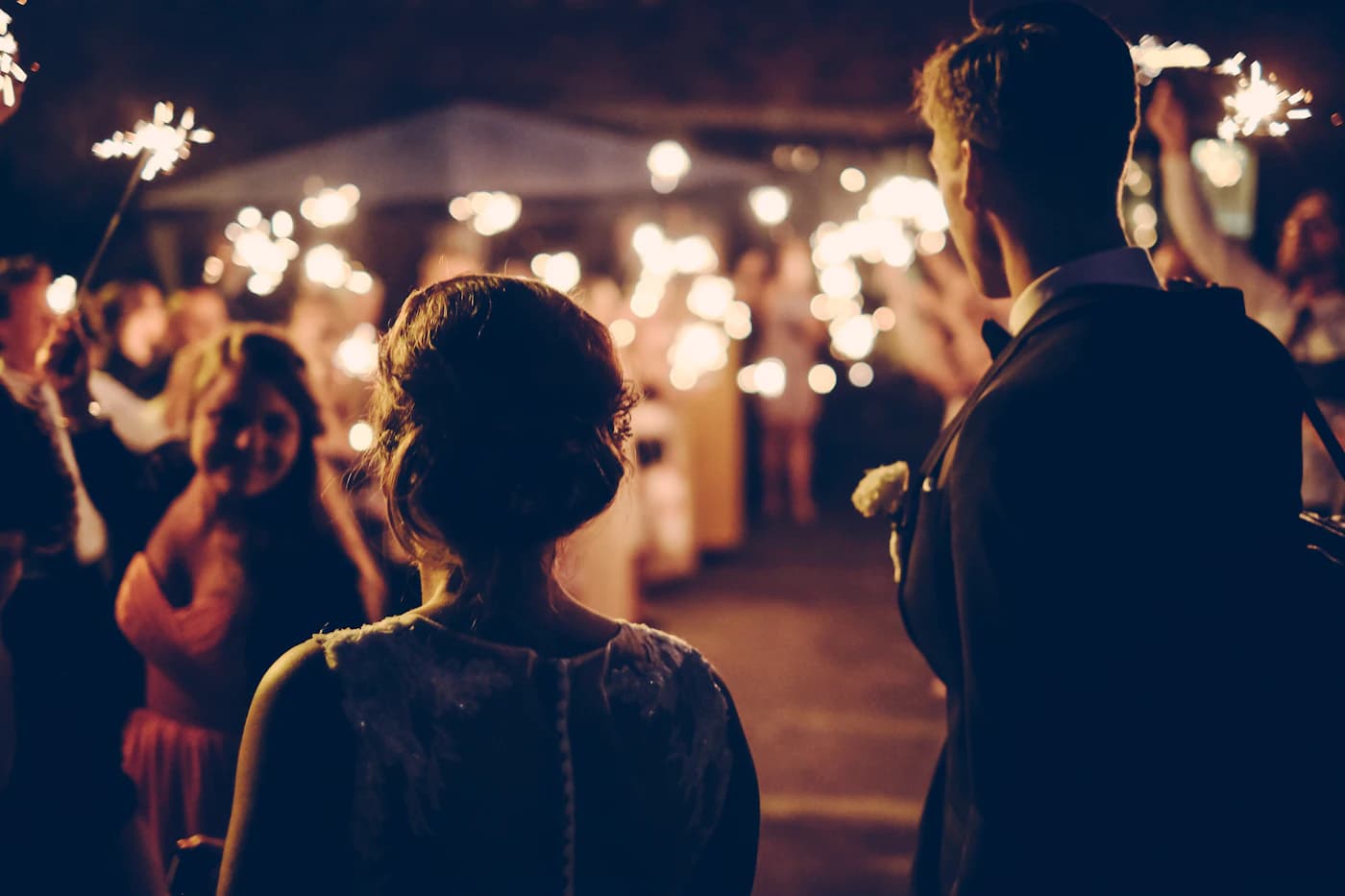 Convidados com sparklers na saída dos noivos, à noite